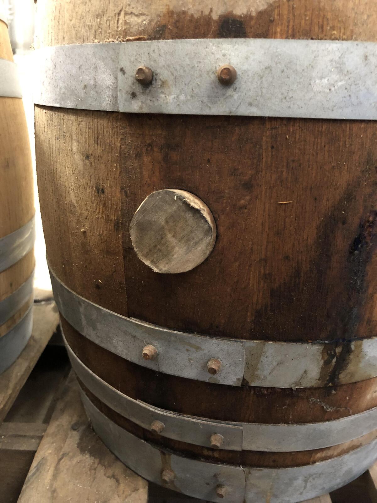 A wooden bung plugs a hole in the side of a wooden barrel